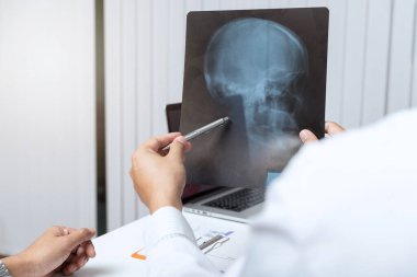 Tıbbi ve sağlık hizmetleri konsepti. Doktor, ofiste masada otururken hastaya röntgen sonuçlarını açıklıyor..