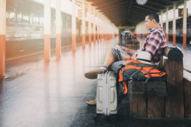 Tren istasyonunda oturan ve harita kullanan gezgin.