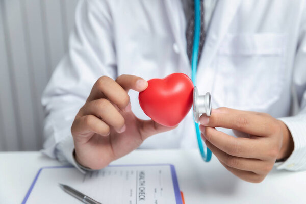 Врач осматривает красный шар в форме сердца со стетоскопом
.