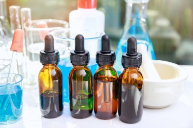 Şişede beher ve laboratuvar bardakları var. İçinde sıvı bulunan bir grup laboratuvar şişesi. Araştırmacılar COVID-19 virüsünü tedavi etmek için aşı ve ilaç geliştiriyorlar..