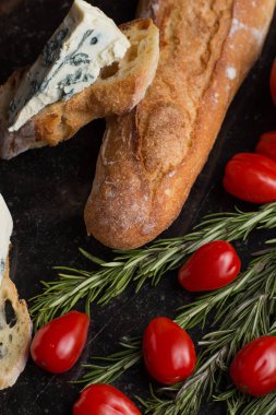 Mavi peynir ile Fransız baget, domates ve siyah mermer masa üzerinde otlar. Fransa ve İtalya geleneksel aperatifler