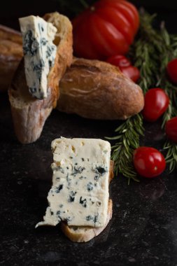 Mavi peynir ile Fransız baget, domates ve siyah mermer masa üzerinde otlar. Fransa ve İtalya geleneksel aperatifler