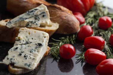 Mavi peynir ile Fransız baget, domates ve siyah mermer masa üzerinde otlar. Fransa ve İtalya geleneksel aperatifler