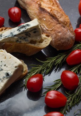 Mavi peynir ile Fransız baget, domates ve siyah mermer masa üzerinde otlar. Fransa ve İtalya geleneksel aperatifler