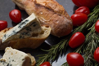 Mavi peynir ile Fransız baget, domates ve siyah mermer masa üzerinde otlar. Fransa ve İtalya geleneksel aperatifler