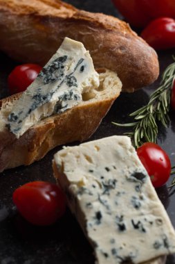 Mavi peynir ile Fransız baget, domates ve siyah mermer masa üzerinde otlar. Fransa ve İtalya geleneksel aperatifler