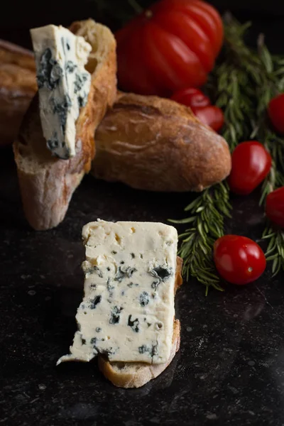 Mavi peynir ile Fransız baget, domates ve siyah mermer masa üzerinde otlar. Fransa ve İtalya geleneksel aperatifler
