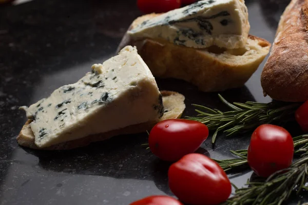 Mavi peynir ile Fransız baget, domates ve siyah mermer masa üzerinde otlar. Fransa ve İtalya geleneksel aperatifler