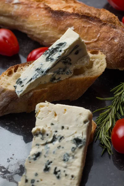 Mavi peynir ile Fransız baget, domates ve siyah mermer masa üzerinde otlar. Fransa ve İtalya geleneksel aperatifler