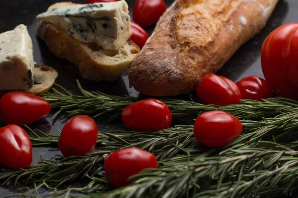Mavi peynir ile Fransız baget, domates ve siyah mermer masa üzerinde otlar. Fransa ve İtalya geleneksel aperatifler
