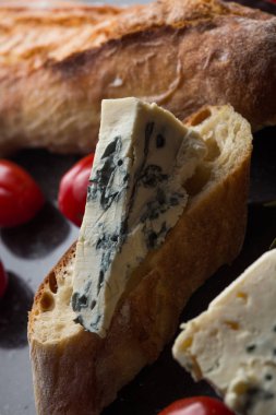 Mavi peynir ile Fransız baget, domates ve siyah mermer masa üzerinde otlar. Fransa ve İtalya geleneksel aperatifler