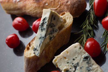Mavi peynir ile Fransız baget, domates ve siyah mermer masa üzerinde otlar. Fransa ve İtalya geleneksel aperatifler