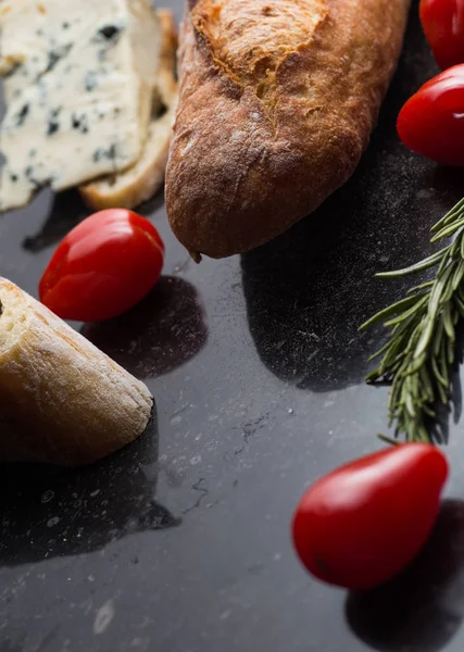 Mavi peynir ile Fransız baget, domates ve siyah mermer masa üzerinde otlar. Fransa ve İtalya geleneksel aperatifler