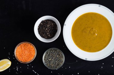 Krem çeşitli mercimek çorbası. Sarı ve yeşil lens, baharat olarak çiğ yemek ve limon siyah backgraund üzerinde. Sağlıklı, lezzetli, lezzetli, vejetaryen yemek. Üstten Görünüm, kopya alanı