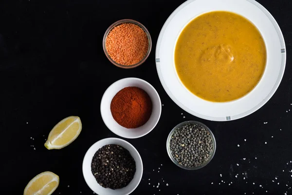 Krem çeşitli mercimek çorbası. Sarı ve yeşil lens, baharat olarak çiğ yemek ve limon siyah backgraund üzerinde. Sağlıklı, lezzetli, lezzetli, vejetaryen yemek. Üstten Görünüm, kopya alanı