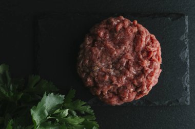 Çiğ biftek. Sığır eti çiğ et baharat, ot ve yumurta sarısı ile kıyılmış. Taze, baharatlı, lezzetli, gurme yemek ile kopya alanı, koyu arka plan üzerinde yakın çekim. Üstten Görünüm.