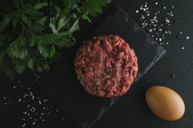 Çiğ biftek. Sığır eti çiğ et baharat, ot ve yumurta sarısı ile kıyılmış. Taze, baharatlı, lezzetli, gurme yemek ile kopya alanı, koyu arka plan üzerinde yakın çekim. Üstten Görünüm.