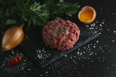 Çiğ biftek. Sığır eti çiğ et baharat, ot ve yumurta sarısı ile kıyılmış. Taze, baharatlı, lezzetli, gurme yemek ile kopya alanı, koyu arka plan üzerinde yakın çekim.