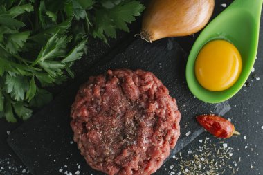 Çiğ biftek. Sığır eti çiğ et baharat, ot ve yumurta sarısı ile kıyılmış. Taze, baharatlı, lezzetli, gurme yemek ile kopya alanı, koyu arka plan üzerinde yakın çekim. Üstten Görünüm