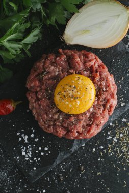 Çiğ biftek. Sığır eti çiğ et baharat, ot ve yumurta sarısı ile kıyılmış. Taze, baharatlı, lezzetli, gurme yemek ile kopya alanı, koyu arka plan üzerinde yakın çekim. Üstten Görünüm.