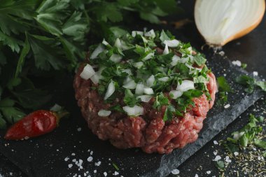 Çiğ biftek. Sığır eti çiğ et baharat, ot ve yumurta sarısı ile kıyılmış. Taze, baharatlı, lezzetli, gurme yemek ile kopya alanı, koyu arka plan üzerinde yakın çekim.