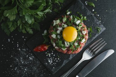 Çiğ biftek. Sığır eti çiğ et baharat, ot ve yumurta sarısı ile kıyılmış. Taze, baharatlı, lezzetli, gurme yemek ile kopya alanı, koyu arka plan üzerinde yakın çekim. Üstten Görünüm.