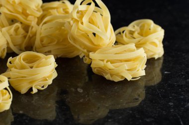 Makarna Tagliatelle mermer masaya düzenlenmiştir. Ham closeup arka plan. Geleneksel İtalyan mutfağı yemek için lezzetli kuru pişmemiş madde. Üstten Görünüm. Kopya alanı