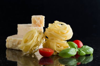 Makarna Tagliatelle, parmesan mermer masaya düzenlenmiştir. Geleneksel İtalyan mutfağı yemek için lezzetli kuru pişmemiş maddeler. Ham closeup arka plan. Üstten Görünüm. Kopya alanı