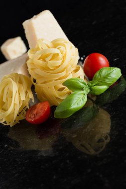 Makarna Tagliatelle, parmesan mermer masaya düzenlenmiştir. Geleneksel İtalyan mutfağı yemek için lezzetli kuru pişmemiş maddeler. Ham closeup arka plan. Üstten Görünüm. Kopya alanı