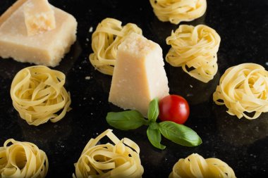Makarna Tagliatelle, parmesan mermer masaya düzenlenmiştir. Geleneksel İtalyan mutfağı yemek için lezzetli kuru pişmemiş maddeler. Ham closeup arka plan. Üstten Görünüm. Kopya alanı