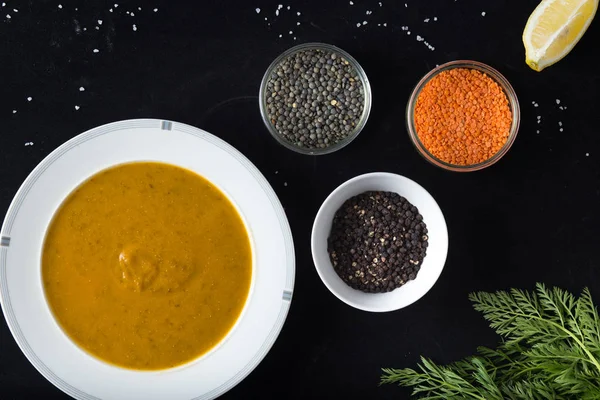 Krem çeşitli mercimek çorbası. Sarı ve yeşil lens, baharat olarak çiğ yemek ve limon siyah backgraund üzerinde. Sağlıklı, lezzetli, lezzetli, vejetaryen yemek. Üstten Görünüm, kopya alanı