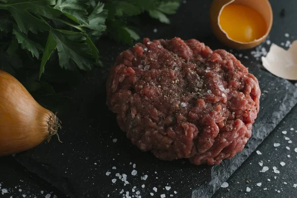 Çiğ biftek. Sığır eti çiğ et baharat, ot ve yumurta sarısı ile kıyılmış. Taze, baharatlı, lezzetli, gurme yemek ile kopya alanı, koyu arka plan üzerinde yakın çekim.