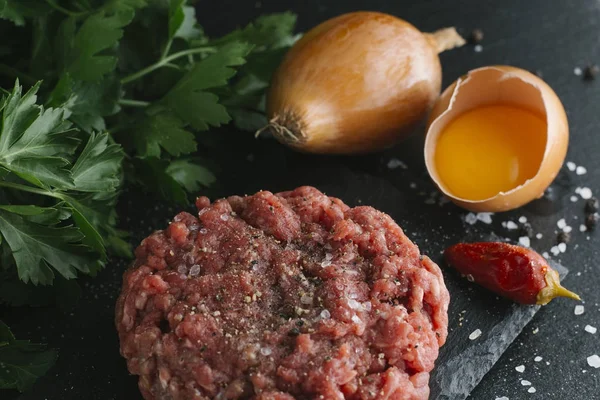 Çiğ biftek. Sığır eti çiğ et baharat, ot ve yumurta sarısı ile kıyılmış. Taze, baharatlı, lezzetli, gurme yemek ile kopya alanı, koyu arka plan üzerinde yakın çekim.