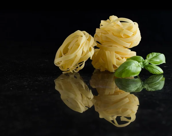 Pasta Tagliatelle arranged on marble table. Raw closeup background. Delicious dry uncooked ingredient for traditional Italian cuisine dish. Top view. Copy space — Stock Photo, Image
