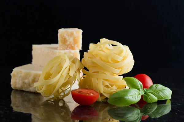 Ζυμαρικά ταλιατέλες, παρμεζάνα τοποθετημένα σε μαρμάρινο τραπέζι. Νόστιμα ξηρό άψητα συστατικά για πιάτο παραδοσιακή ιταλική κουζίνα. RAW closeup φόντο. Το Top view. Χώρο αντίγραφο — Φωτογραφία Αρχείου