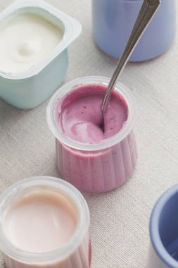 Plastik yoğurt ürün yelpazesine beyaz Tekstil arka plan üzerinde kaseler. Doğal ve sağlıklı meyve, diyet, gurme tatlı granola kahvaltı için. Tatlı yoğurt portre