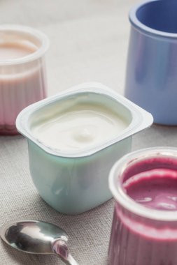 Plastik yoğurt ürün yelpazesine beyaz Tekstil arka plan üzerinde kaseler. Doğal ve sağlıklı meyve, diyet, gurme tatlı granola kahvaltı için. Tatlı yoğurt portre