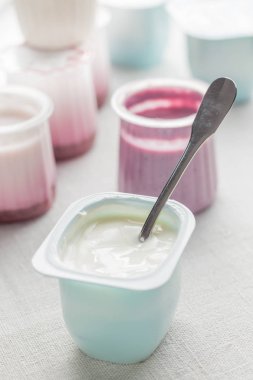 Plastik yoğurt ürün yelpazesine beyaz Tekstil arka plan üzerinde kaseler. Doğal ve sağlıklı meyve, diyet, gurme tatlı granola kahvaltı için. Tatlı yoğurt portre