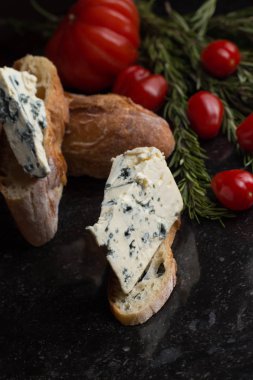 Mavi peynir ile Fransız baget, domates ve siyah mermer masa üzerinde otlar. Fransa ve İtalya geleneksel aperatifler