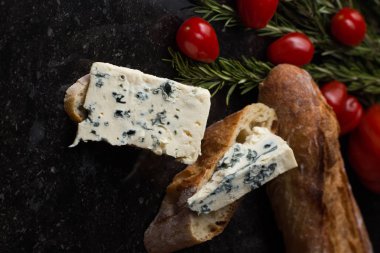Mavi peynir ile Fransız baget, domates ve siyah mermer masa üzerinde otlar. Fransa ve İtalya geleneksel aperatifler