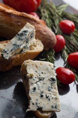 Mavi peynir ile Fransız baget, domates ve siyah mermer masa üzerinde otlar. Fransa ve İtalya geleneksel aperatifler