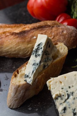 Mavi peynir ile Fransız baget, domates ve siyah mermer masa üzerinde otlar. Fransa ve İtalya geleneksel aperatifler