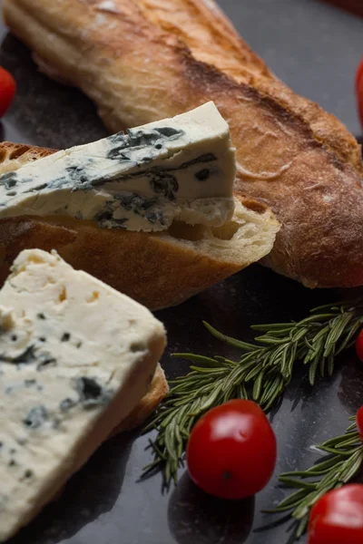 Mavi peynir ile Fransız baget, domates ve siyah mermer masa üzerinde otlar. Fransa ve İtalya geleneksel aperatifler
