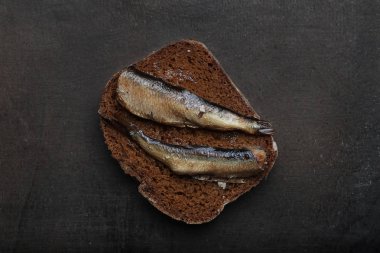 Atıştırmalıklar ile sardalye siyah Çavdarlı ekmek dilimlenmiş. Riga geleneksel lezzetli yemek. Koyu arka plan üzerinde hamsi füme. Üstten Görünüm