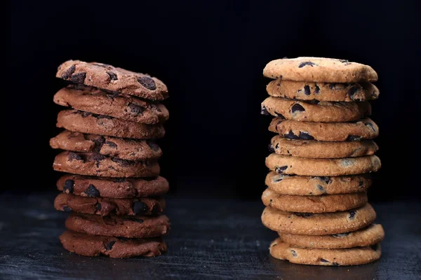 Cookies with Chocolate chip on dark wooden table. Two cookies towers isolated on black background
