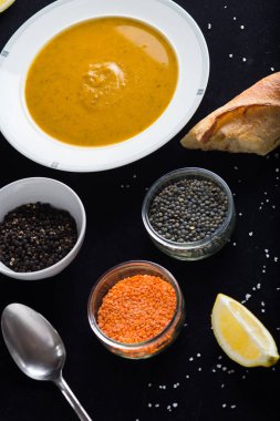 Krem çeşitli mercimek çorbası. Sarı ve yeşil lens, baharat olarak çiğ yemek ve limon siyah backgraund üzerinde. Sağlıklı, lezzetli, lezzetli, vejetaryen yemek. Üstten Görünüm, kopya alanı