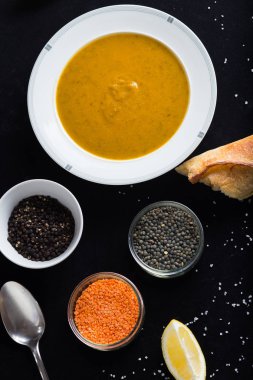 Krem çeşitli mercimek çorbası. Sarı ve yeşil lens, baharat olarak çiğ yemek ve limon siyah backgraund üzerinde. Sağlıklı, lezzetli, lezzetli, vejetaryen yemek. Üstten Görünüm, kopya alanı