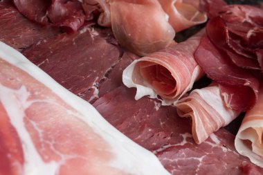 Jambon karışımı. Jambon. Geleneksel İtalyan ve İspanyol Tuzlama, Sigara, otlar ve karanlık taş zemin üzerine domates kuru tedavi çanak - jamon Serrano ve prosciutto crudo dilimlenmiş. Uzay kopyalayın. Portre