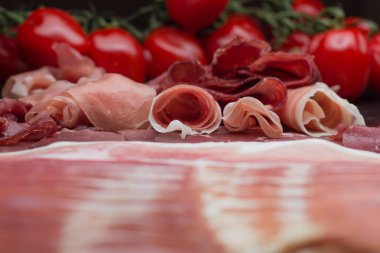 Jambon karışımı. Jambon. Geleneksel İtalyan ve İspanyol Tuzlama, Sigara, otlar ve karanlık taş zemin üzerine domates kuru tedavi çanak - jamon Serrano ve prosciutto crudo dilimlenmiş. Uzay kopyalayın. Portre