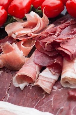 Jambon karışımı. Jambon. Geleneksel İtalyan ve İspanyol Tuzlama, Sigara, otlar ve karanlık taş zemin üzerine domates kuru tedavi çanak - jamon Serrano ve prosciutto crudo dilimlenmiş. Uzay kopyalayın. Portre